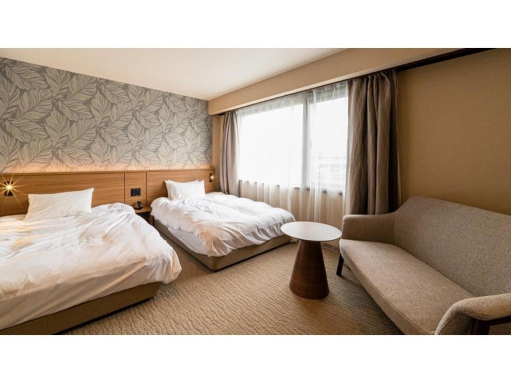 TobeにあるKutsurogi no Yado Juraku - Vacation STAY 03510vのベッド2台とソファが備わるホテルルームです。