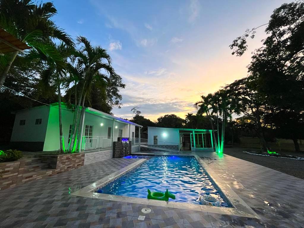 a swimming pool in front of a house with green lights at Finca Nirvana. in Agua de Dios