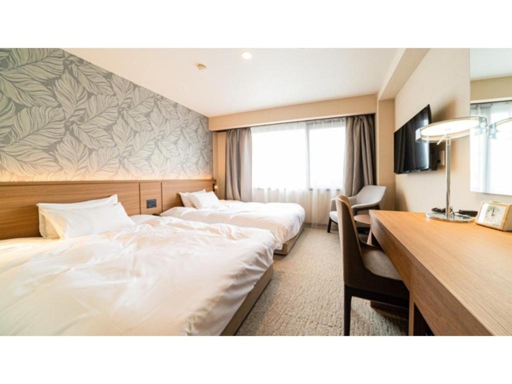 a hotel room with two beds and a desk at Kutsurogi no Yado Juraku - Vacation STAY 03508v in Tobe