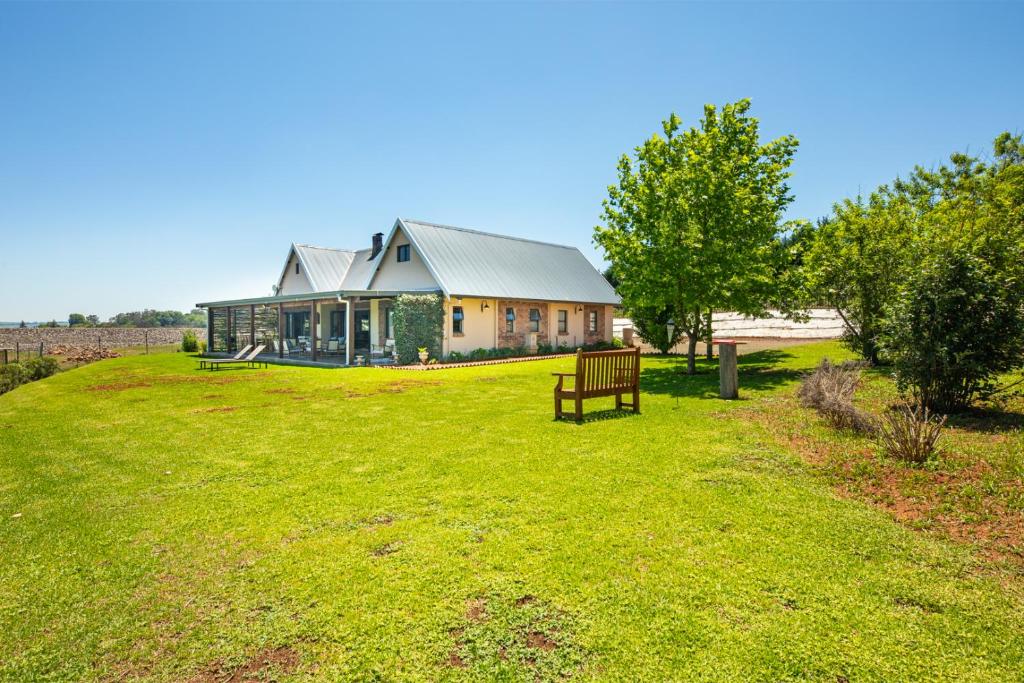 a house on a hill with a bench in the grass at Midlands Lakehouse in Rosetta