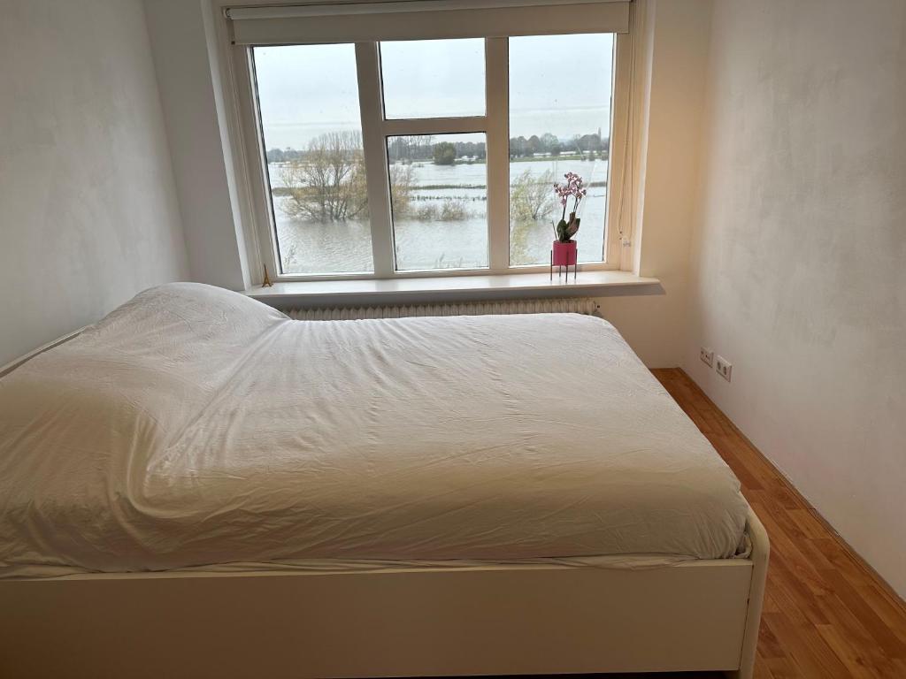 a white bed in a room with a window at Mooie kamer uitzicht op de ijssel/ Nice room with beautiful view of the Ijssel river in Wijhe
