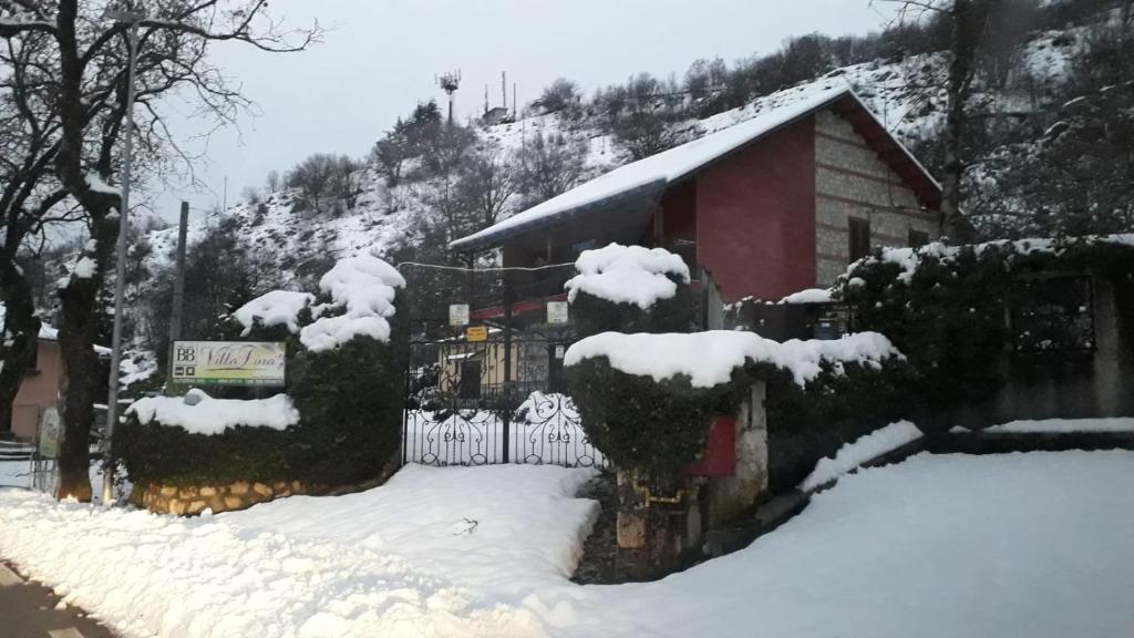 a house with a fence covered in snow at B&B Villa Tina in Alfedena