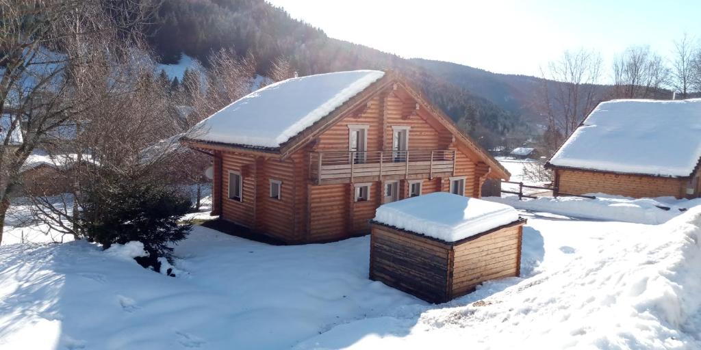 una cabaña de madera en la nieve con nieve en Le Chardonneret, en La Bresse