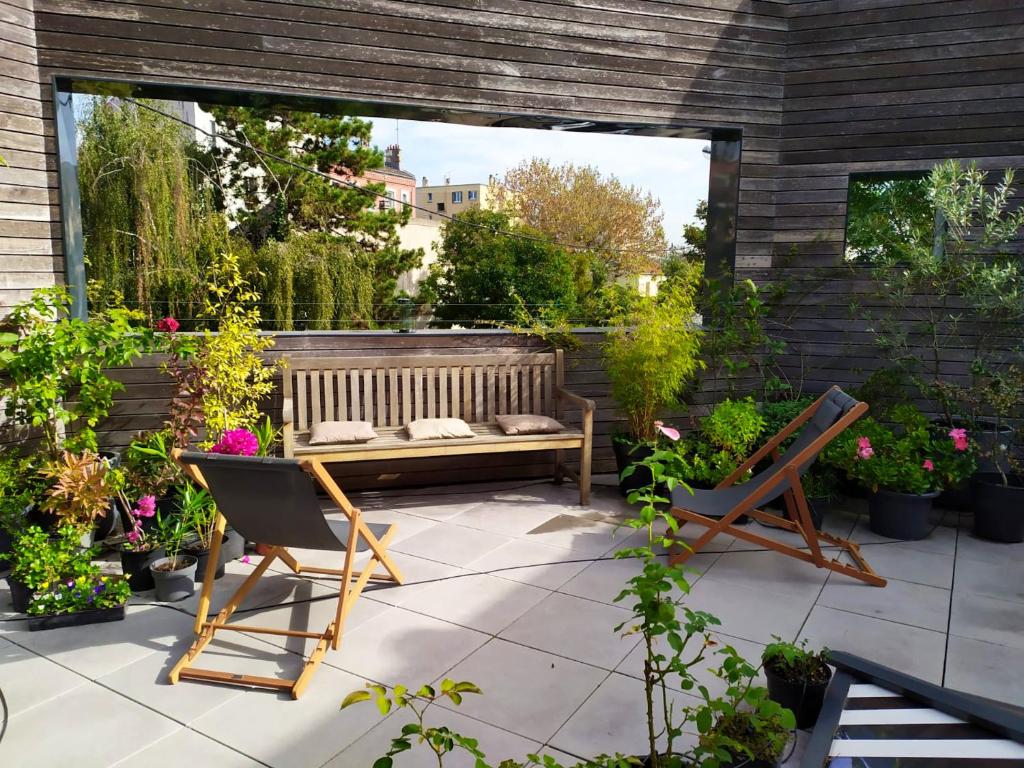 - une terrasse avec un banc et un bouquet de plantes dans l'établissement Appartement charmant à Saint-Ouen avec terrasse & vue sur ville, à Saint-Ouen