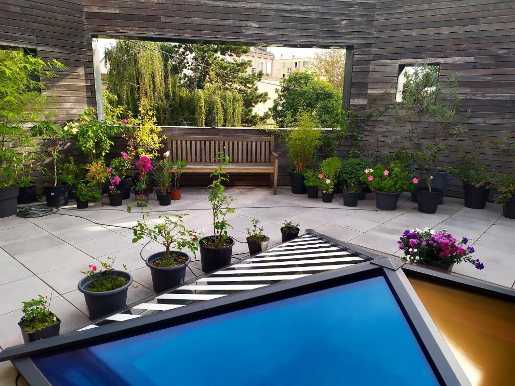 a garden with potted plants on a patio with a bench at Appartement de 2 chambres avec vue sur la ville terrasse amenagee et wifi a Saint Ouen in Saint-Ouen