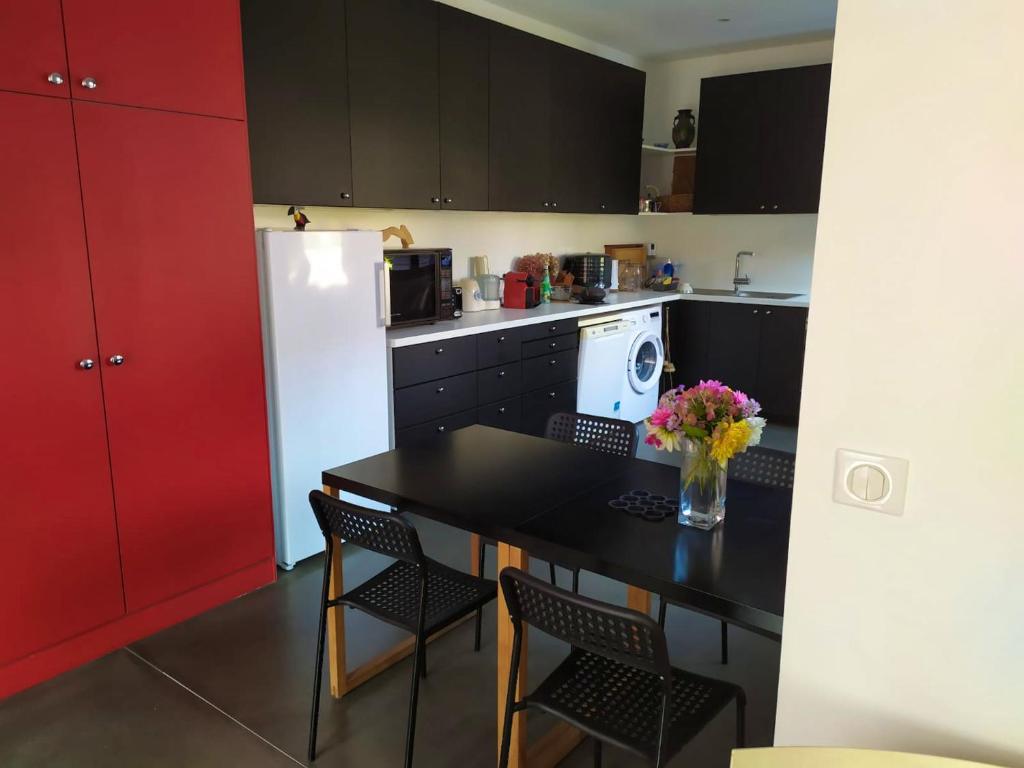 a kitchen with a black table and a white refrigerator at Appartement de 2 chambres avec vue sur la ville terrasse amenagee et wifi a Saint Ouen in Saint-Ouen