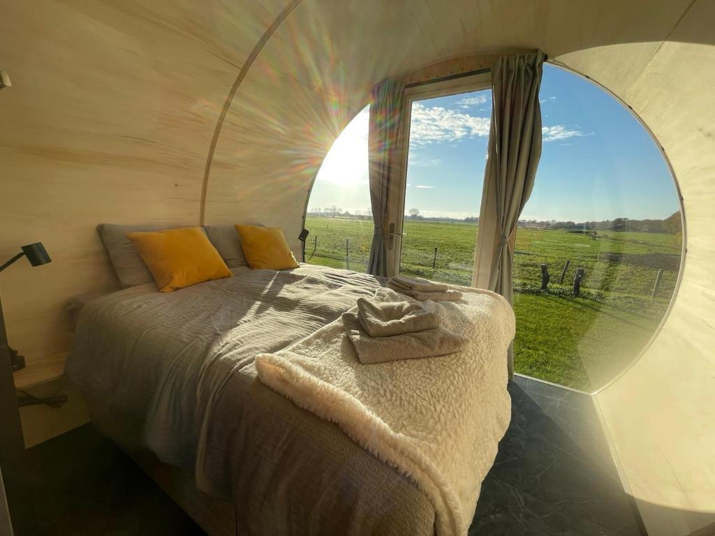 een slaapkamer met een bed en een groot raam bij Ontspan in de Droomstam in Dalfsen