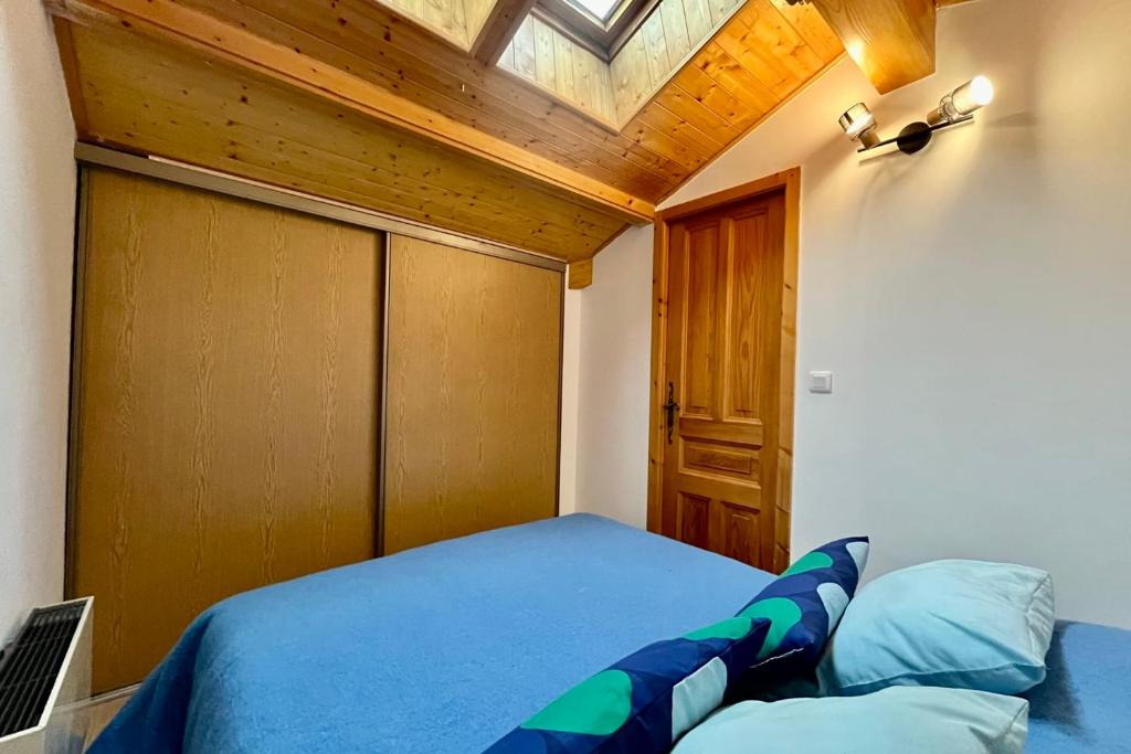 a bedroom with a blue bed with a wooden ceiling at Apartment with balcony and exceptional view in Saint-Gervais-les-Bains