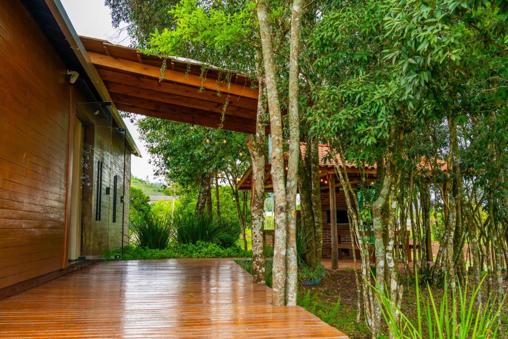 una pasarela de madera que conduce a una casa con árboles en Caravaggio Container Inn (7 min d Caminho d Pedras), en Farroupilha