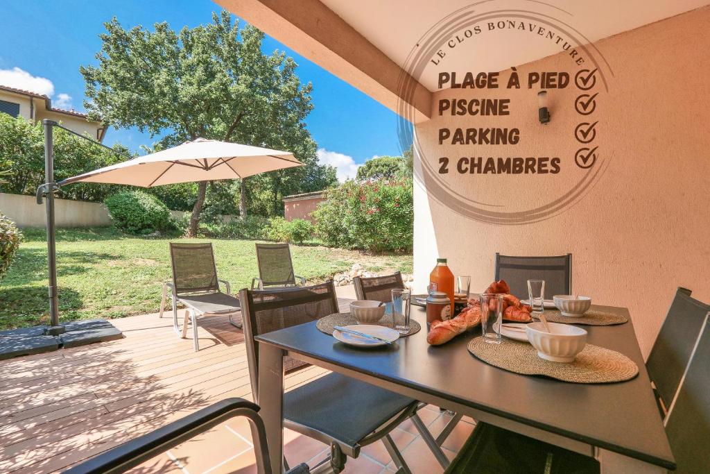 eine Terrasse mit einem Tisch, Stühlen und einem Sonnenschirm in der Unterkunft Chant des Vagues Saint Tropez VIII in Saint-Tropez