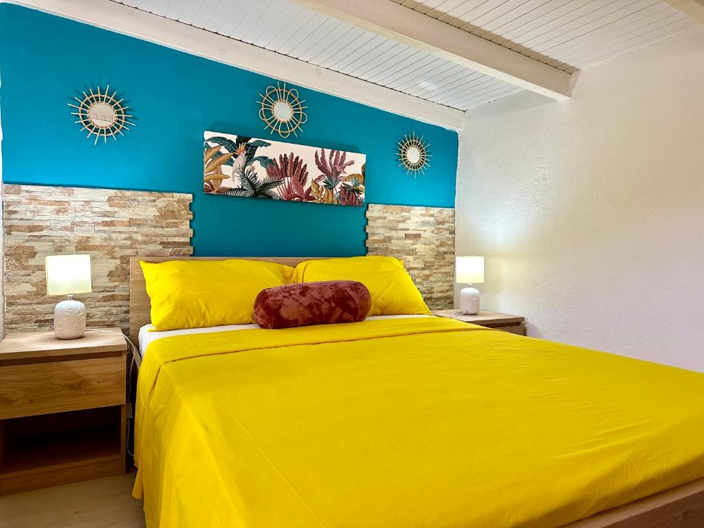 a bedroom with a yellow bed and blue walls at Au cœur de la plaine 2 in Capesterre-Belle-Eau