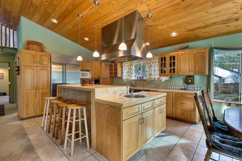 una cocina con armarios de madera y una isla de cocina con taburetes en Sequoia Chalet, en Stateline