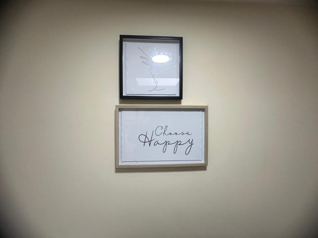 two framed pictures on a wall with the words always happy at Experience Downing Road Dagenham 2 bedroom Apartment in Dagenham