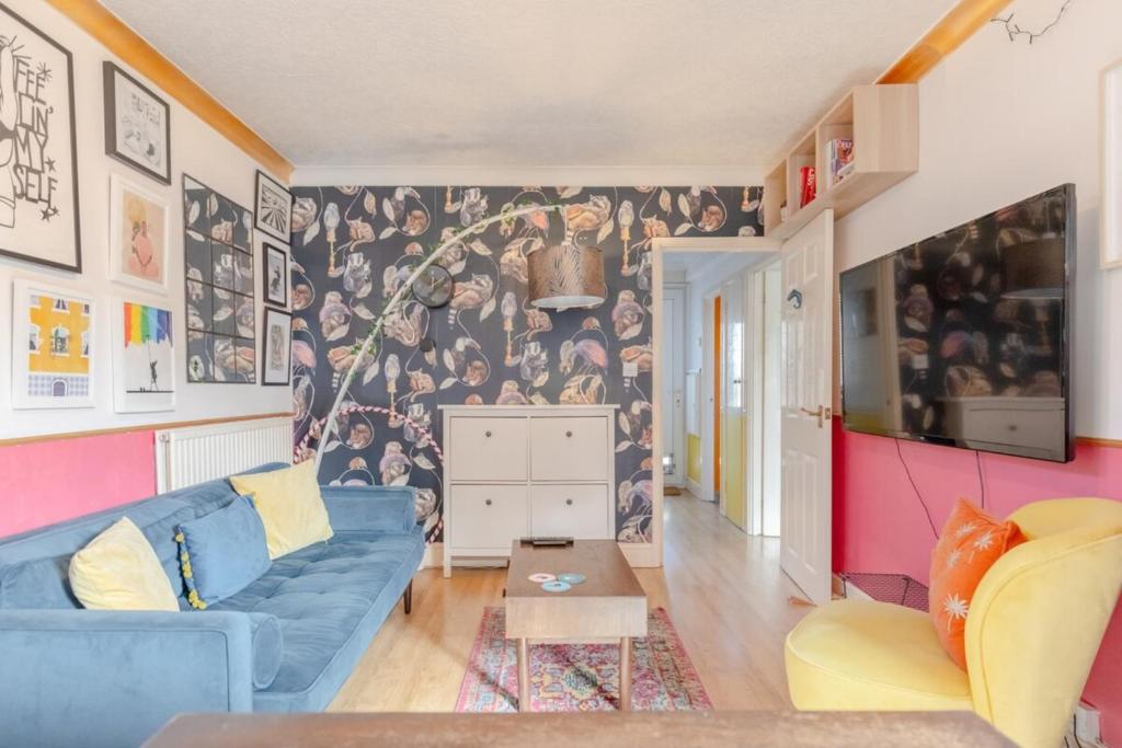 a living room with a blue couch and a wall mural at Vibrant 1BD Flat - 8 Mins to Dalston Hackney! in London