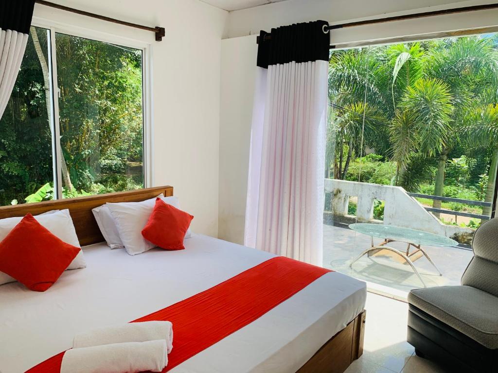 a bedroom with a bed and a window and a chair at Chill House safari resort in Udawalawe