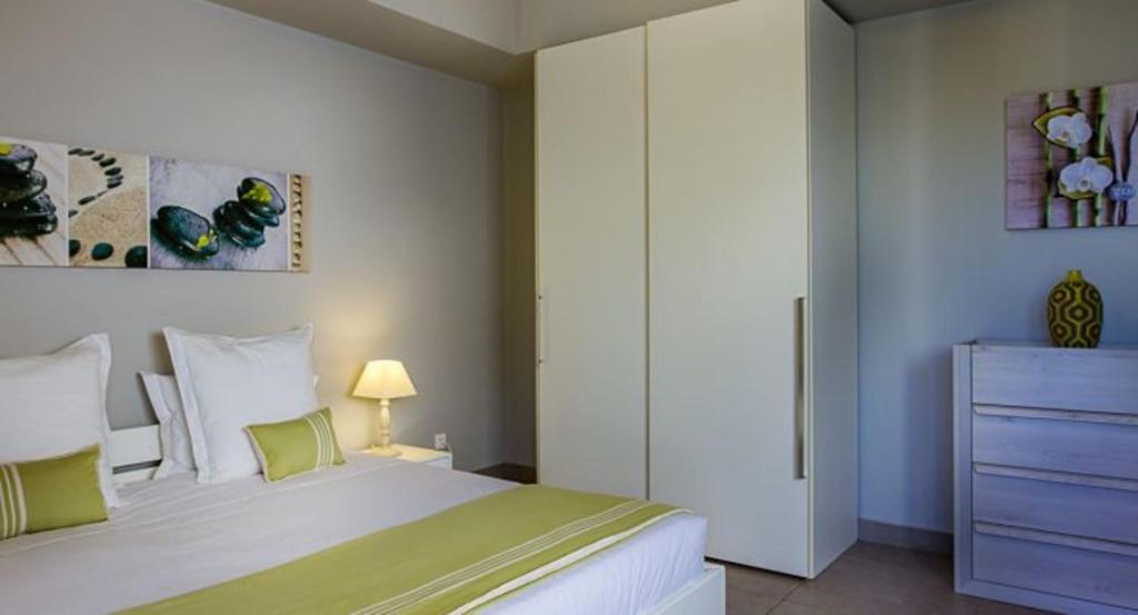ein Schlafzimmer mit einem großen weißen Bett und einer Kommode in der Unterkunft Villas Cap Est OFFRE SPECIALE PONT DE MAI 1 NUIT OFFERTE in Le François