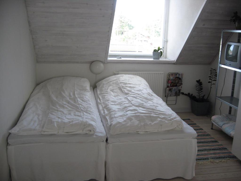2 camas en una habitación pequeña con ventana en B&B Korsørvej, en Herning