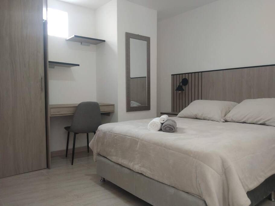 a bedroom with a bed with a desk and a chair at Acogedor apartamento con sala de TV in Sabaneta
