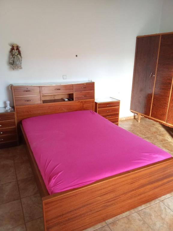 a bedroom with a large wooden bed with pink sheets at house FYNTIKAKH - SKALA in Anopoli Sfakion