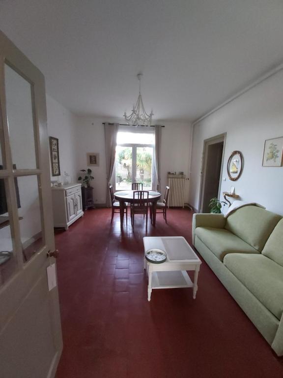 un salon avec un canapé vert et une table dans l'établissement Villa Victoire - Maison - couple 2 personnes, à Rochefort