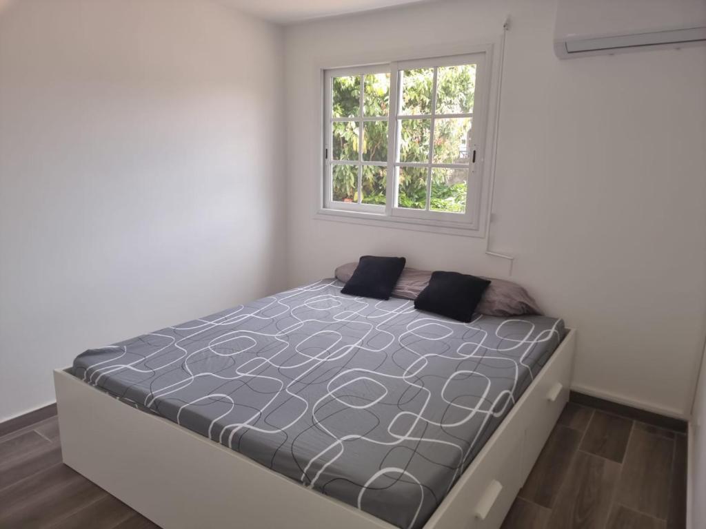 Bett in einem weißen Zimmer mit Fenster in der Unterkunft Delices du Papillon in Petit-Bourg