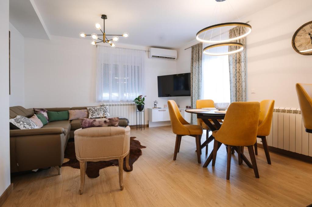 een woonkamer met een bank en een tafel en stoelen bij Nika apartman in Surčin