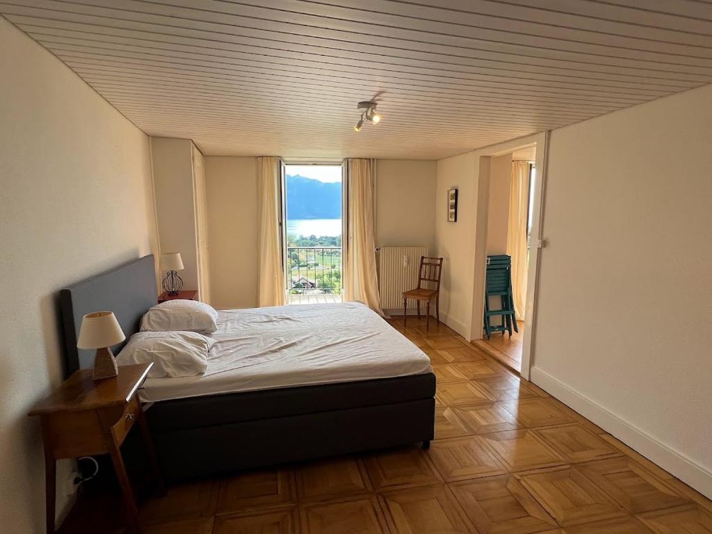 - une chambre avec un lit et une grande fenêtre dans l'établissement La Vigneronne, Chailly-Montreux, à Montreux