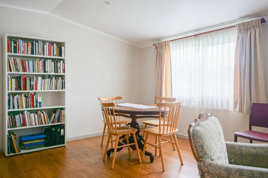 ein Esszimmer mit einem Tisch, Stühlen und Bücherregalen in der Unterkunft A orilla del rio, depto 2D/1B in Valdivia