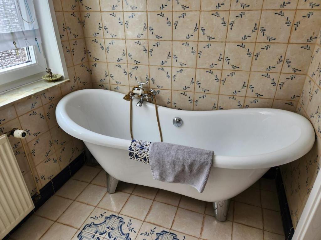 a white bath tub in a bathroom with a tile wall at Apartment 16, Im Zentrum von Braunlage in Braunlage