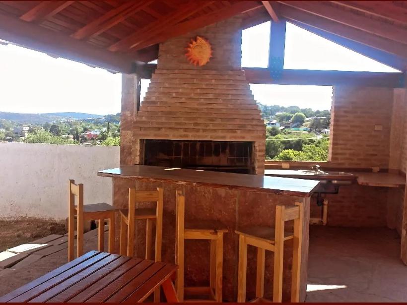 cocina al aire libre con chimenea, mesa y sillas en Chalet " La Maruca " en Villa Carlos Paz
