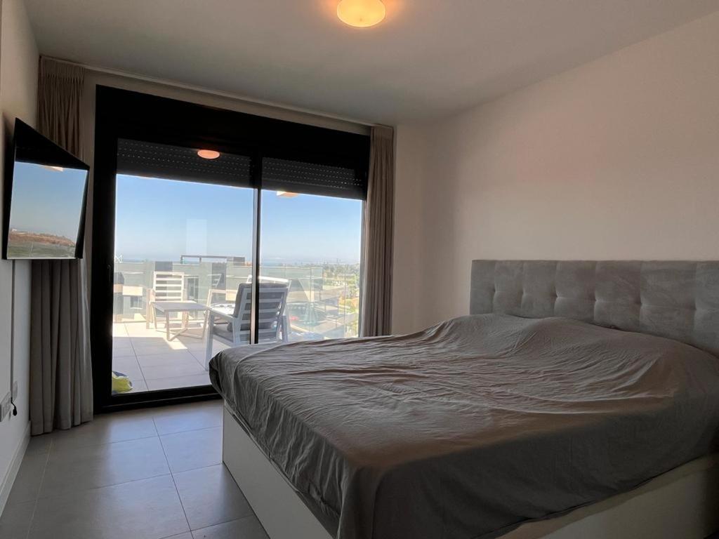 een slaapkamer met een bed en uitzicht op een balkon bij Ático lujo OASIS in Estepona
