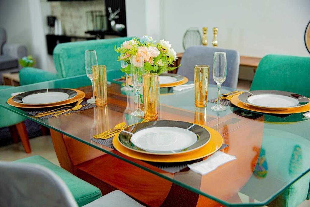 una mesa de cristal con platos y flores. en Moderno y acogedor departamento, en Tacna