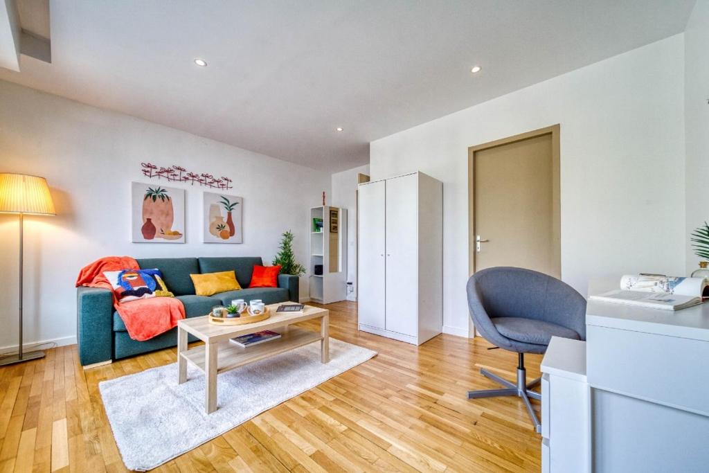 a living room with a blue couch and a table at Le stade Clémenceau in Grenoble