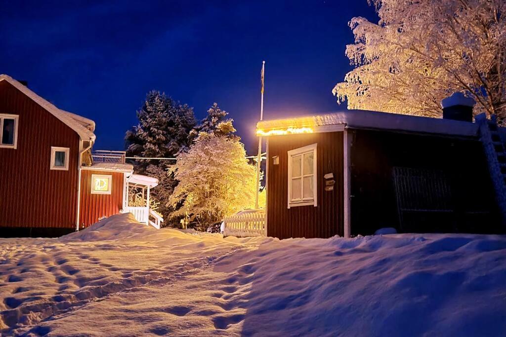 a house with a light on it in the snow at Idyllic vacation home near lake: nature&fireplace in Stöde