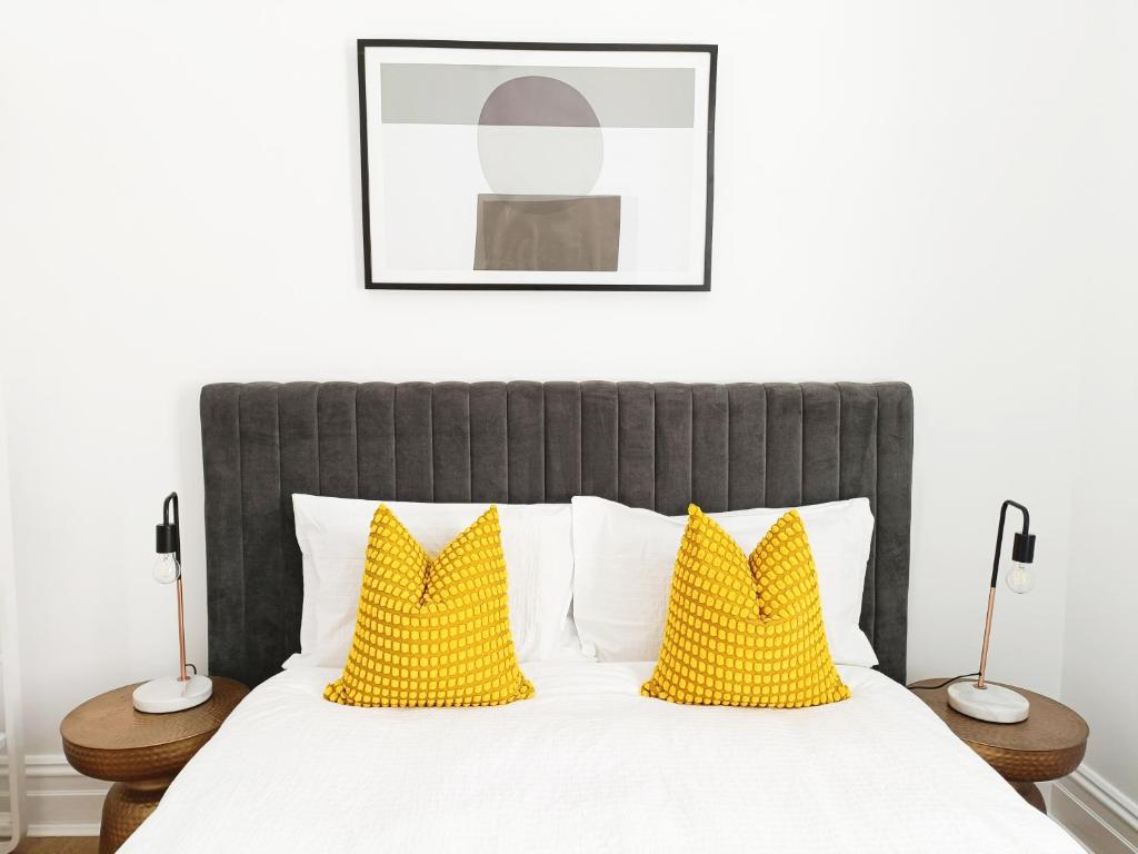 Un dormitorio con una cama grande con almohadas amarillas. en Beautiful Queen Room 1Min Walk to Station with 60Inch TV, en Sídney