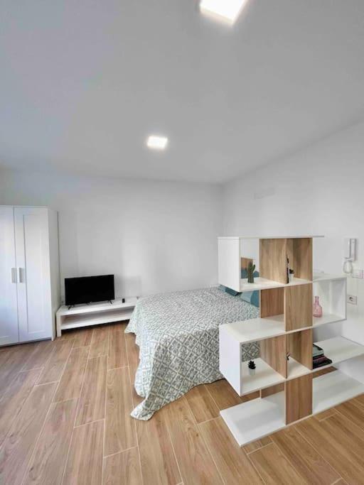 1 dormitorio blanco con 1 cama y suelo de madera en Estudio nuevo en Benicarló, en Benicarló