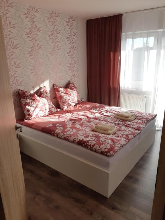 Una cama con sábanas rojas y almohadas en un dormitorio en Vilka Čachtice en Čachtice
