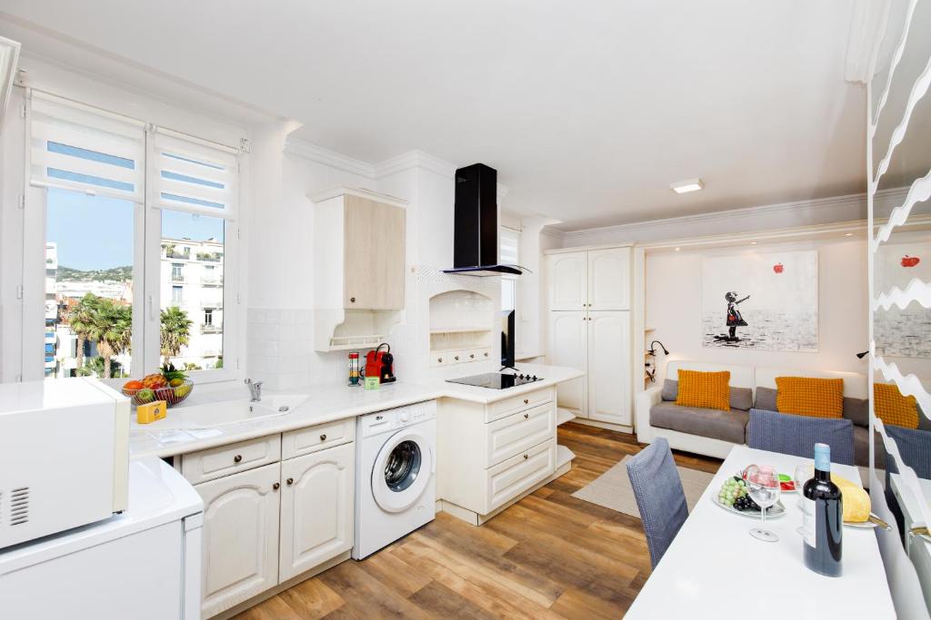 une cuisine avec des armoires blanches et un salon dans l'établissement Dolce Vita YourHostHelper, à Cannes