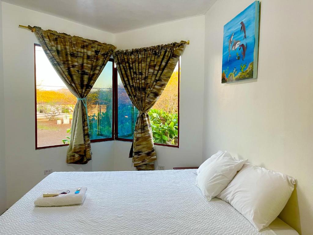 a bedroom with a bed and two windows at Hostal Vista al Mar in Puerto Baquerizo Moreno