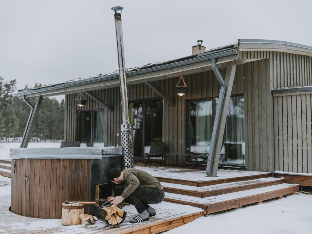 Green Valley vacation homes في Žocenes Ciems: رجل امام بيت في الثلج