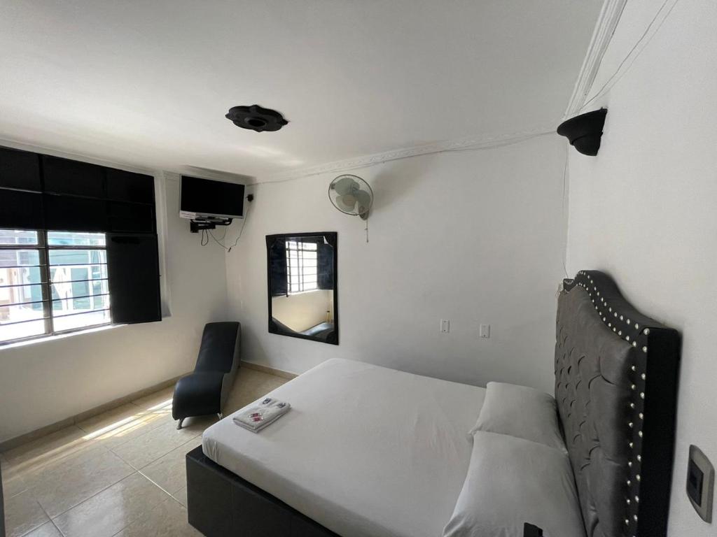 a bedroom with a bed and a chair and a mirror at Residencia del Oriente in Bucaramanga