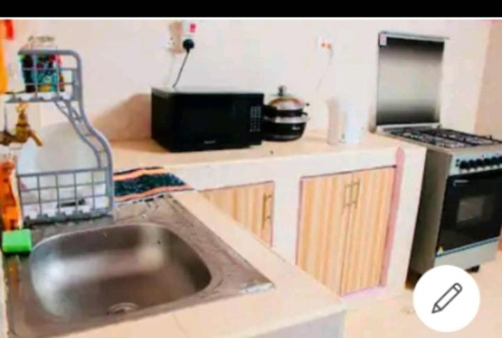 eine Küche mit einer Spüle und einer Mikrowelle in der Unterkunft @princess Dee in Meru