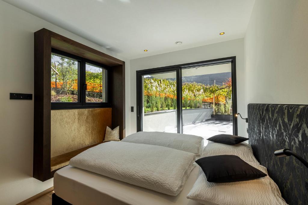 Erbacher Living Nature Apartments Suites في بولسانو: غرفة نوم بسرير ونافذة كبيرة
