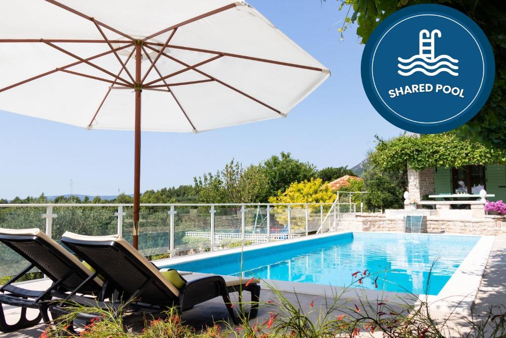 a pair of chairs and an umbrella next to a swimming pool at House Wood in Orebić