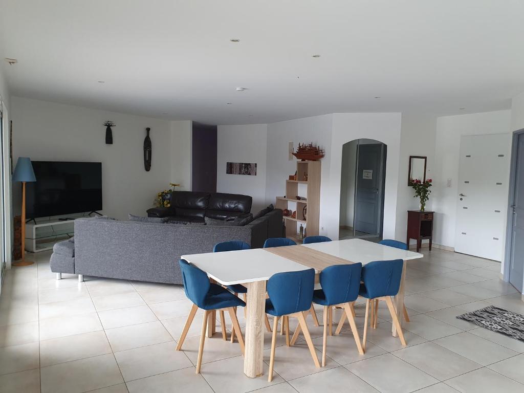 a living room with a table and blue chairs at villa 15 personnes avec piscine et terrain de pétanque in Puysserampion