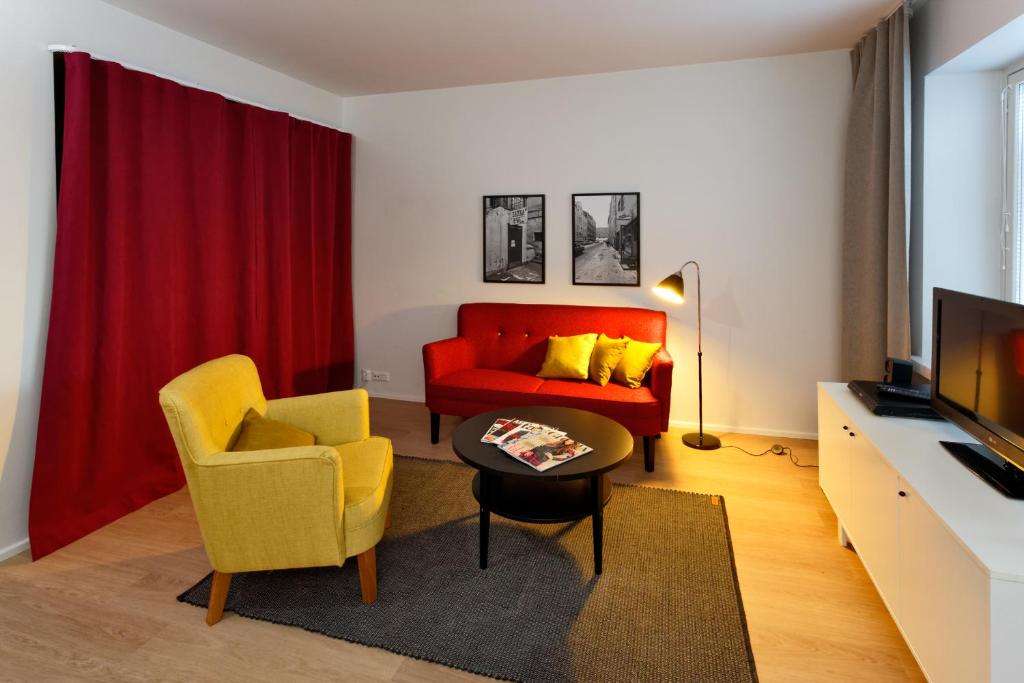 a living room with a red couch and yellow chairs at Forenom Serviced Apartments Helsinki Kruununhaka in Helsinki