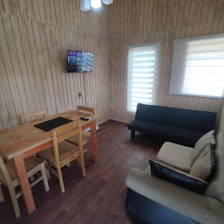 a living room with a table and a couch at Cabañas altos de la chacra , 2 dormitorios in Castro