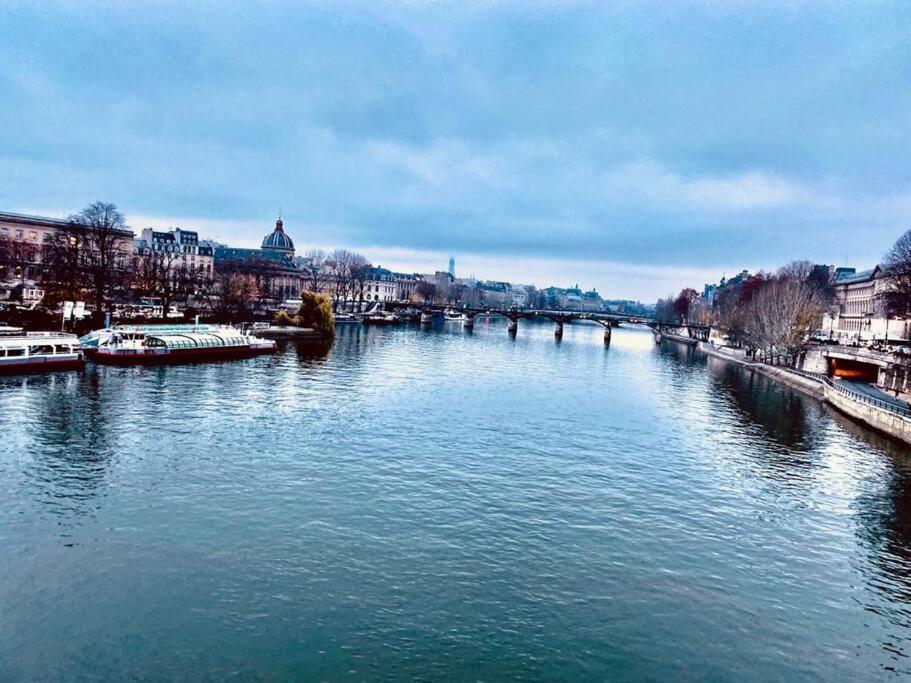 uma vista para um rio com barcos sobre ele em Le Cœur de l’Île Saint-Louis, you will love it! em Paris