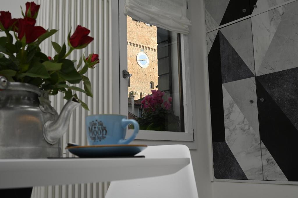 een tafel met een blauwe beker en een vaas met rozen bij Ca' Milla Apartment Noale Centro Storico in Noale
