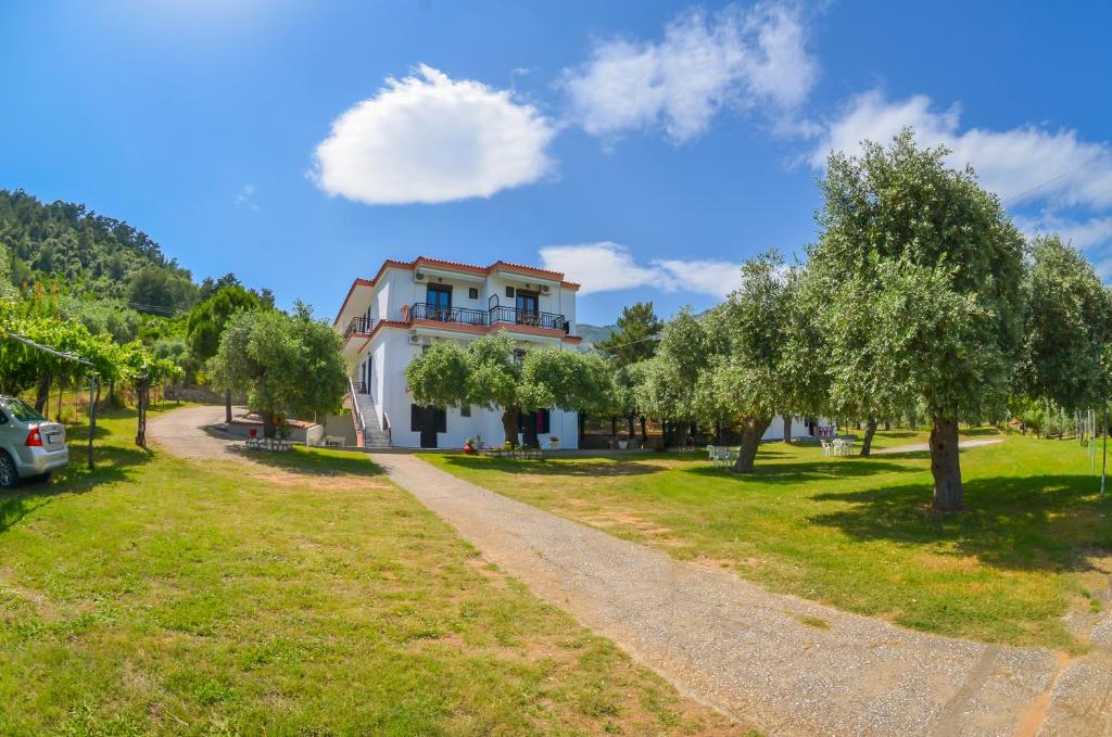a villa with a lawn and trees in front of it at Pension Assos in Koinyra